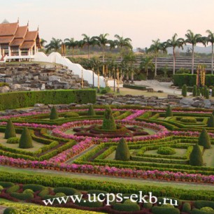 Демонстрационный сад с ландшафтным дизайном в стиле регулярного французского парка. На его фоне видны тайские храмы
